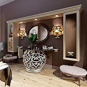 _Mobile bagno sospeso in legno, con cappello in finitura nocciola dorato, cat. B, ante a specchio bronzo e maniglia medea in finitura foglia argento tortora, cat. C, base lavabo medea in finitura foglia argento tortora, cat. C, monoblocco in cristallo finitura granadine, cat. A, rubinetteria trefori</br>
_Specchiera Orlando in legno, finitura prugna laccato lucido, cat. A</br>
_Applique Medea in finitura foglia argento tortora, cat. C</br>
_Pouff nouvelle in legno, con rivestimento capitonnè in tessuto, cat. C e struttura in finitura prugna laccato lucido, cat. A</br>
_Biancheria bagno collezione Medea</br>
_Accessori bagno vari