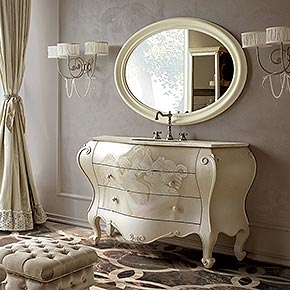 _Mobile bagno Marchese in legno, finitura avorio craquelet e decoro tre grazie, lavabo sottopiano in marmo bianco perlino, rubinetteria trefori retrò in cromo</br>
_Specchiera Arlando in legno, finitura burro laccato lucido, cat. A</br>
_Applique Avril in metallo, finitura foglia argento tortora, cat. C, paralume in tessuto plissè ponge/05, cat. A con perle</br>
_Vetrine Lester in finitura nocciola dorato, cat. B e anta in specchio bronzo, maniglia medea in foglia oro tortora, cat. C