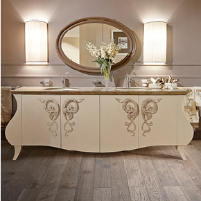 _Mobile bagno Glamour 
         in legno, finitura cameo craquelet, cat. B, 
         con maniglia suite in finitura foglia argento tortora, 
         cat. C, top lavabo in vetro decorato in foglia argento 
         tortora, cat. C, rubinetti mono fori round.
        <br>
        _Specchiera Orlando 
         in legno, finitura prugna laccato lucido, cat. A.
        <br>
        _Applique Alì 
         con paralume plissè in tessuto, cat. A.
        <br>
        _Accessori bagno.