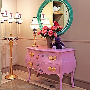 _Comò Tiffany in legno, finitura fuxia lucido, cat. A con decoro butterfly e maniglia di metallo Fiocco in finitura foglia oro, cat. C</br>
_Specchiera Orlando in legno, finitura turchese laccato lucido, cat. A</br>
_Lampada da terra Fiocco in metallo con 5 bracci, finitura basamento in foglia oro, cat. C e bracci in finitura pistacchio, cat. B, paralume in tessuto luce/37, cat. B, con fiocchi</br>
_Abatjour Fiocco in metallo, finitura in foglia oro, cat. C e paralume in tessuto luce/37, cat. B, con fiocchi