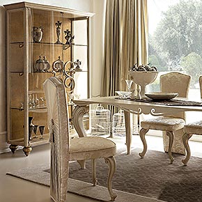 _Tavolo Lord con piano in metallo e gambe lavorate, finitura top macramè in cameo bronze, cat. B</br>
_ Sedie Ester capotavola, rivestimento tessuto, cat. D, piedi nocciola dorato, cat. B</br>
_ vetrina Medea con struttura in nocciola dorato, cat. B, con piedi, maniglie e schienale finitura foglia oro tortora, cat. C</br>
_ Tappeto Noblesse